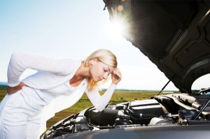 woman-looking-under-hood-of-broken-car